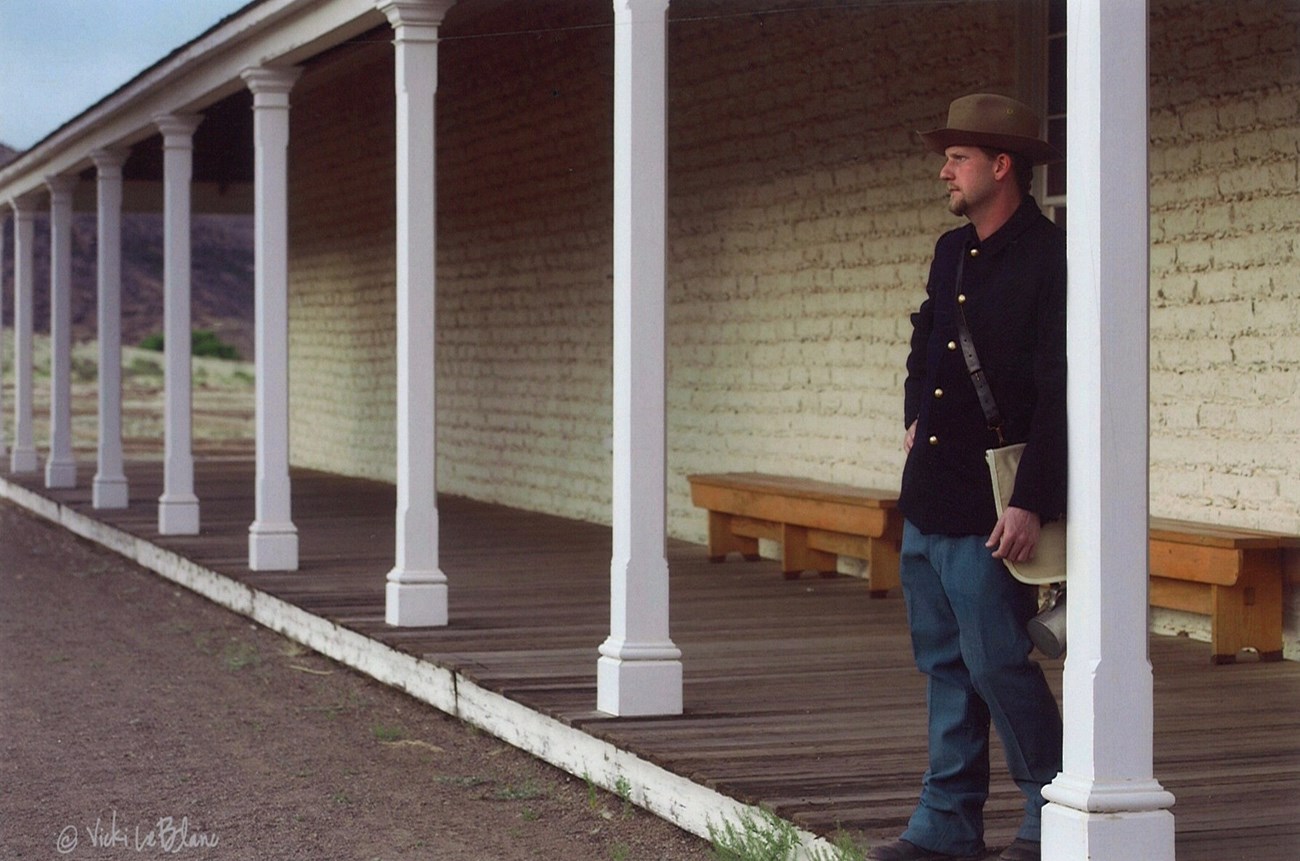 Soldier standing in front of barracks leaning on column