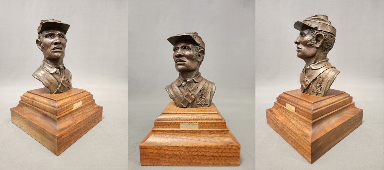 Bronze.  Head and upper torso of 9th Cavalry soldier, Troop D.  Gaze is to right.  Wears Army blouse, kepi with insignia, Congressional Medal of Honor, carbine sling with 1-toothed buckle in front. On walnut base with brass plaque: "BUFFALO SOLDIER"