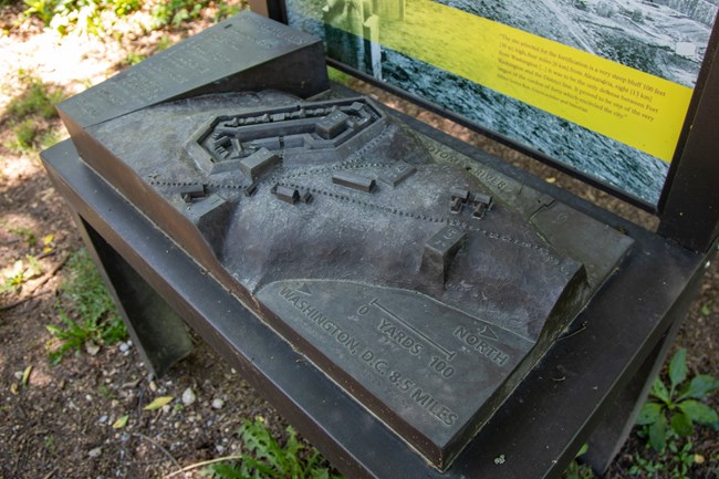 A bronze relief map of a fort at the top of a hill with braille labels.