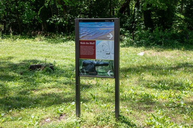 A sign with a map, images, and text in a grassy area.