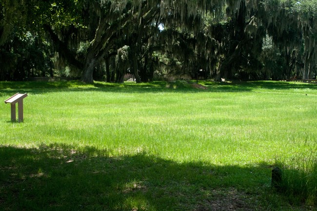 green grass lot with information sign in background