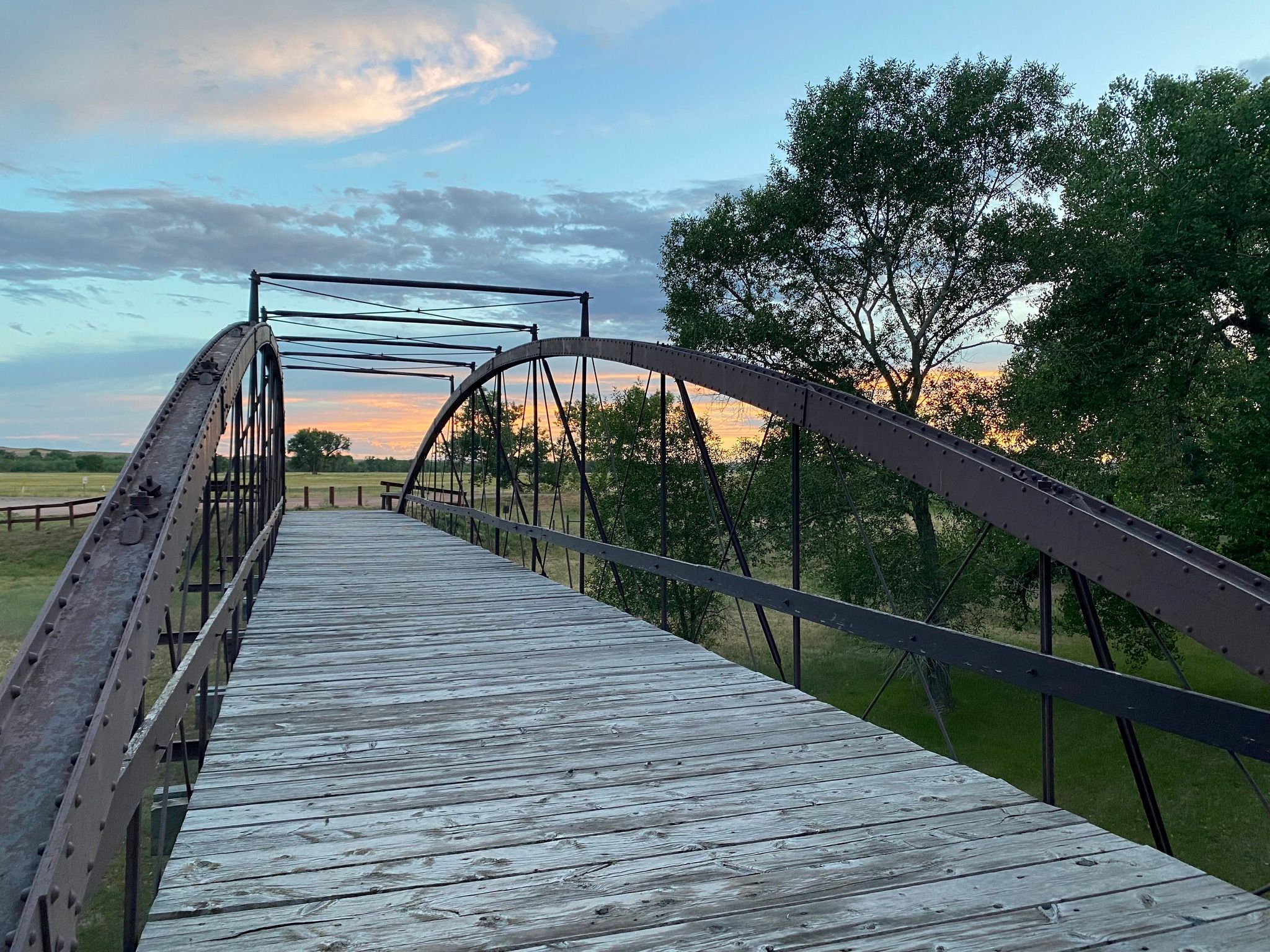 Old Army Bridge - NPS Photo An iron and wooden bridge at sunset looking across to a field and the horizon.