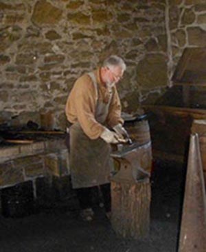 Man in leather apron hammering iron on an anvil. Man in leather apron hammering iron on an anvil.