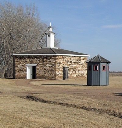 Reconstructed sandstone blockhouse with wooden sentry box in foreground.