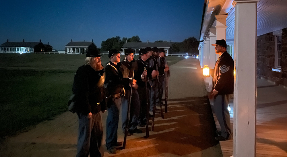 Candlelight Tour Scene Several soldiers are lined up in front of the barracks at night.