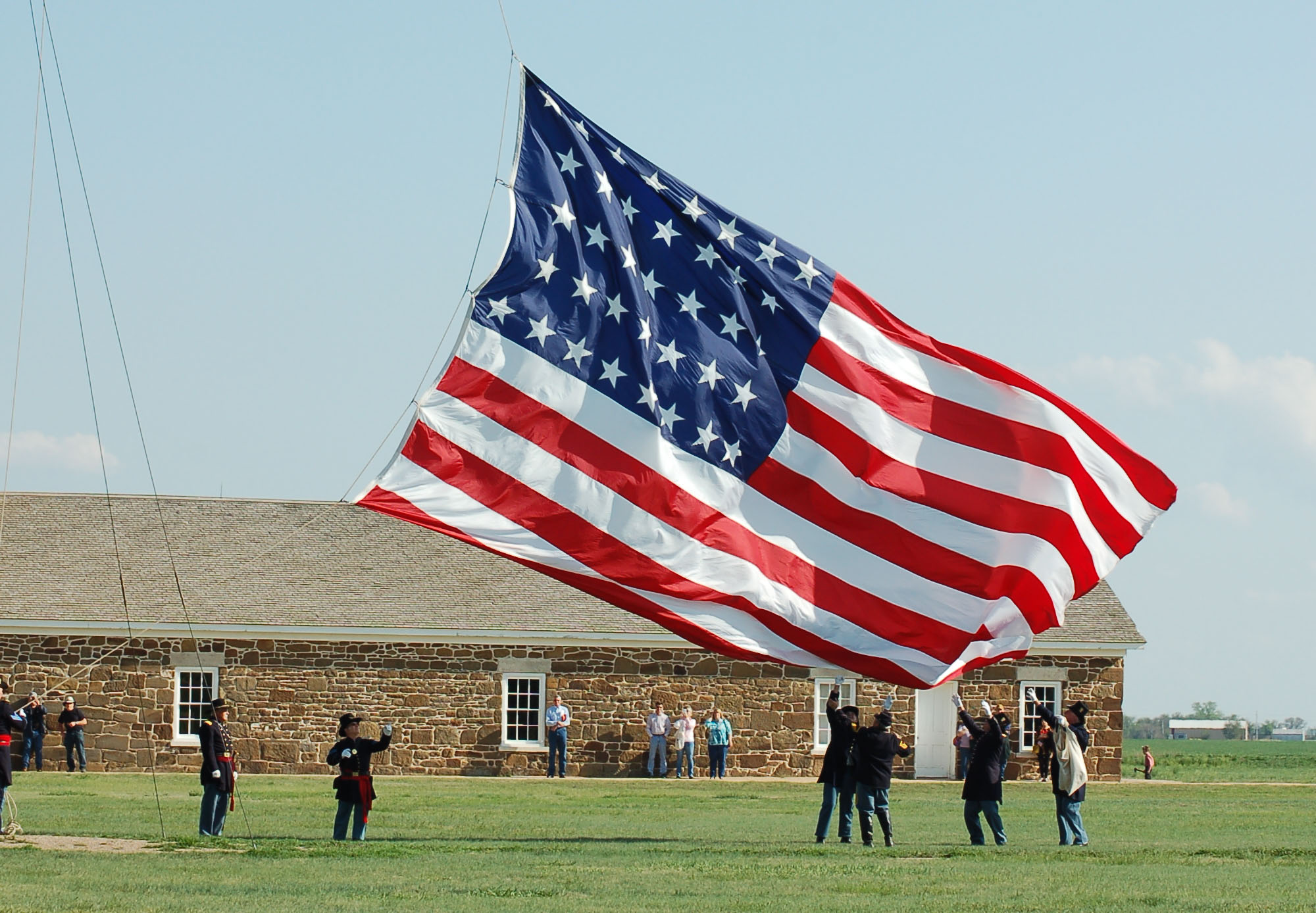 Flag Retreat Several people catch a large flag as it's lowered from a flag pole.