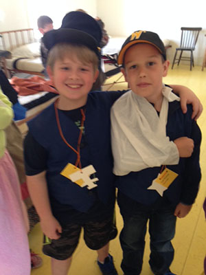 Two young boys in partial 19th century army dress and fake bandages.