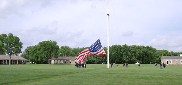 Men in 19th century U.S. Army uniforms taking down large American flag. Men in 19th century U.S. Army uniforms taking down large American flag.