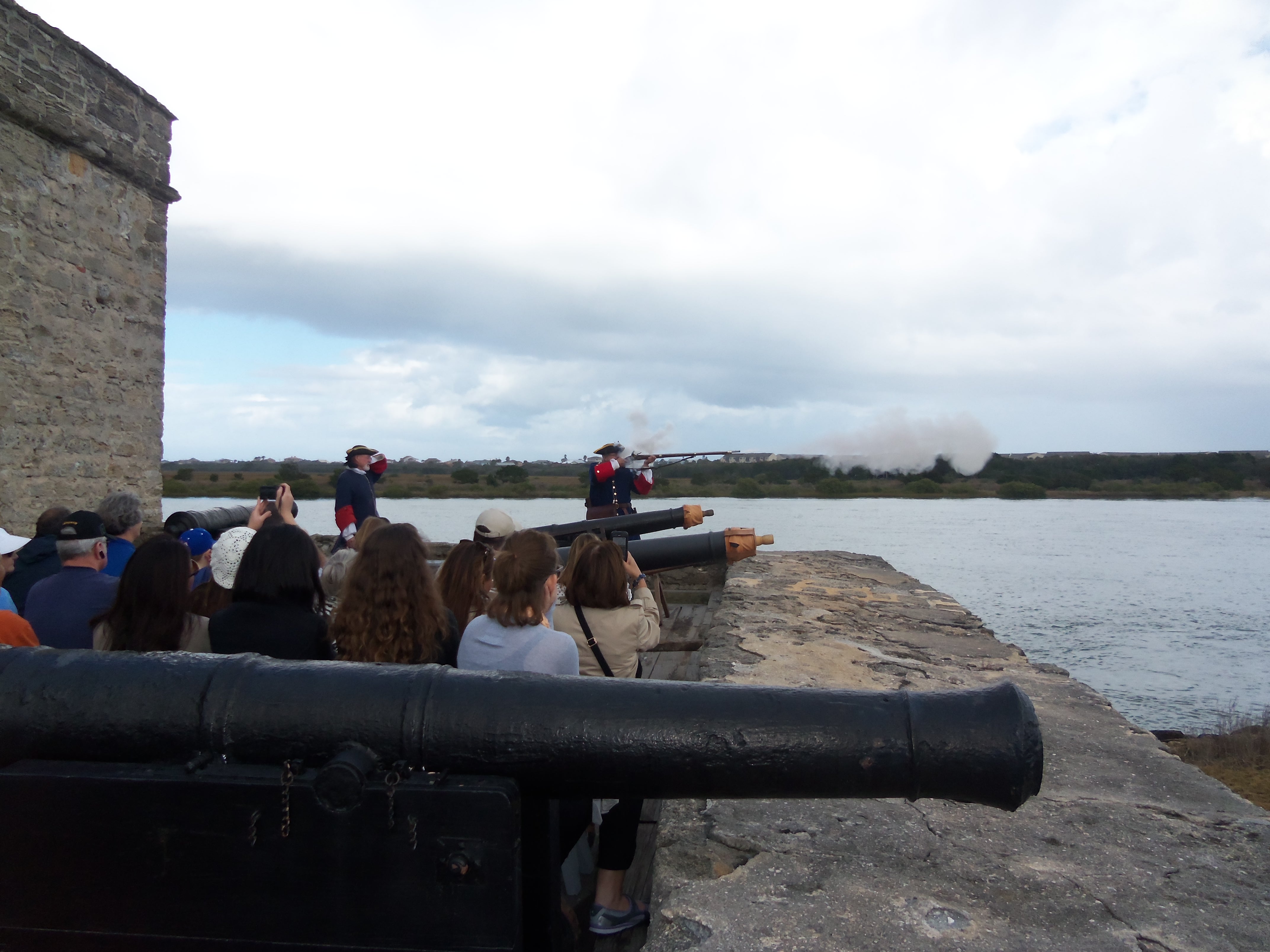 Visitors watch soldiers fire a musket
