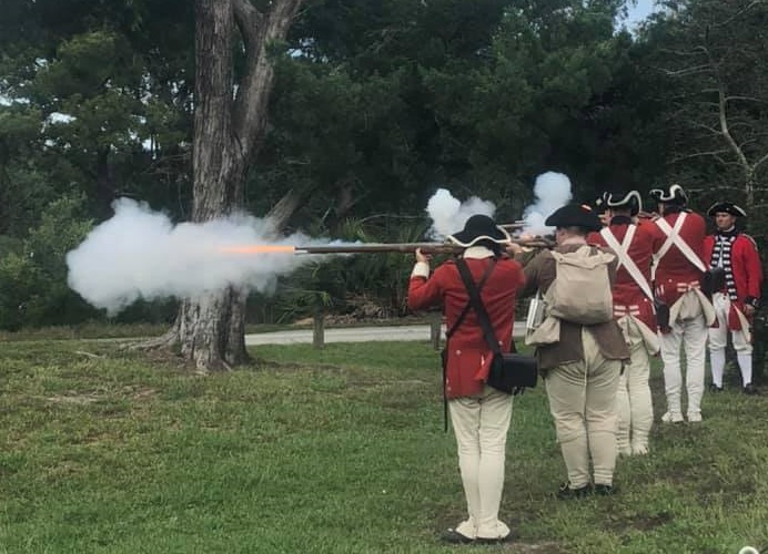 A line of British soldiers fire a musket volley