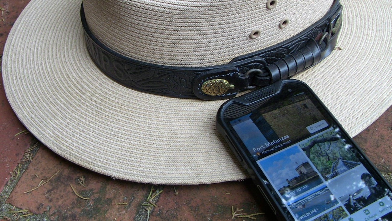 Ranger hat sitting next to phone with park app on screen.