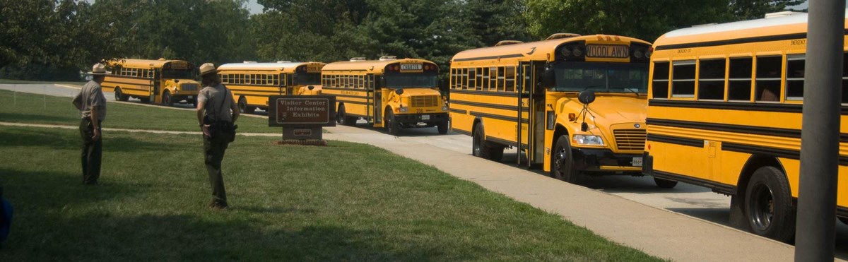 Rangers observing a row of school buses entering the park.