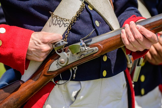 A close up of a living historian loading a musket.
