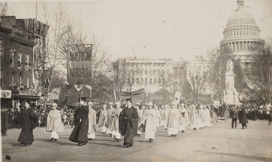 Nurses marching in a suffrage parade in front of the United States Capital building.