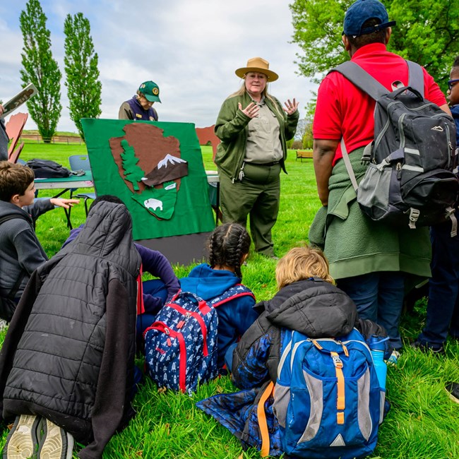 Park rangers leading a program on the symbolism of the National Parks Service logo