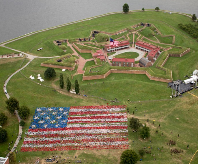 Aerial view of thousands of students creating a living flag on the lawn in front of the historic star fort