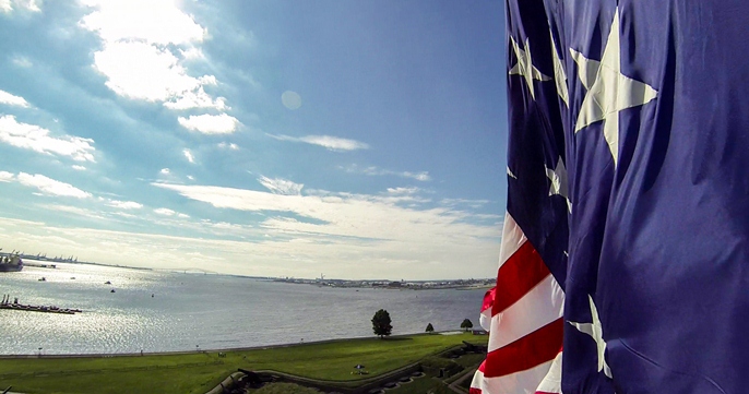 The Star-Spangled Banner waves over Fort McHenry with the Baltimore Harbor in the background