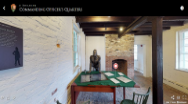 Image of the inside of a brick building with a statue standing behind a desk.