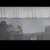 Image of a video showing the backs of two men looking out over the water to a group of tall ships.