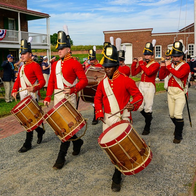 Field musicians in War of 1812 uniform marching in fort