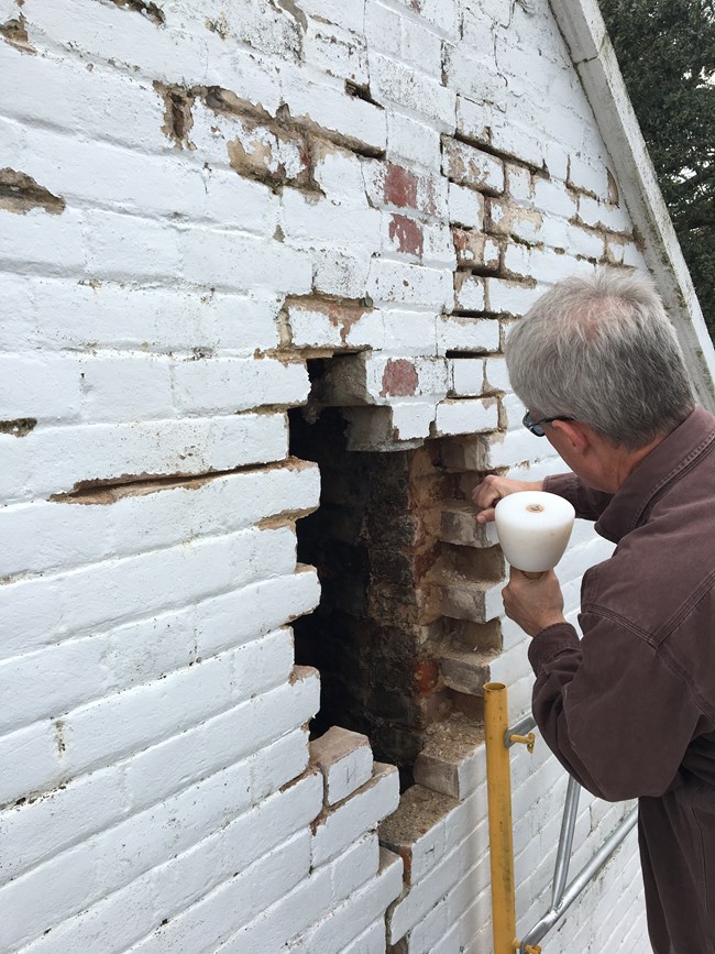 Preservation specialist repairs section of chimney.