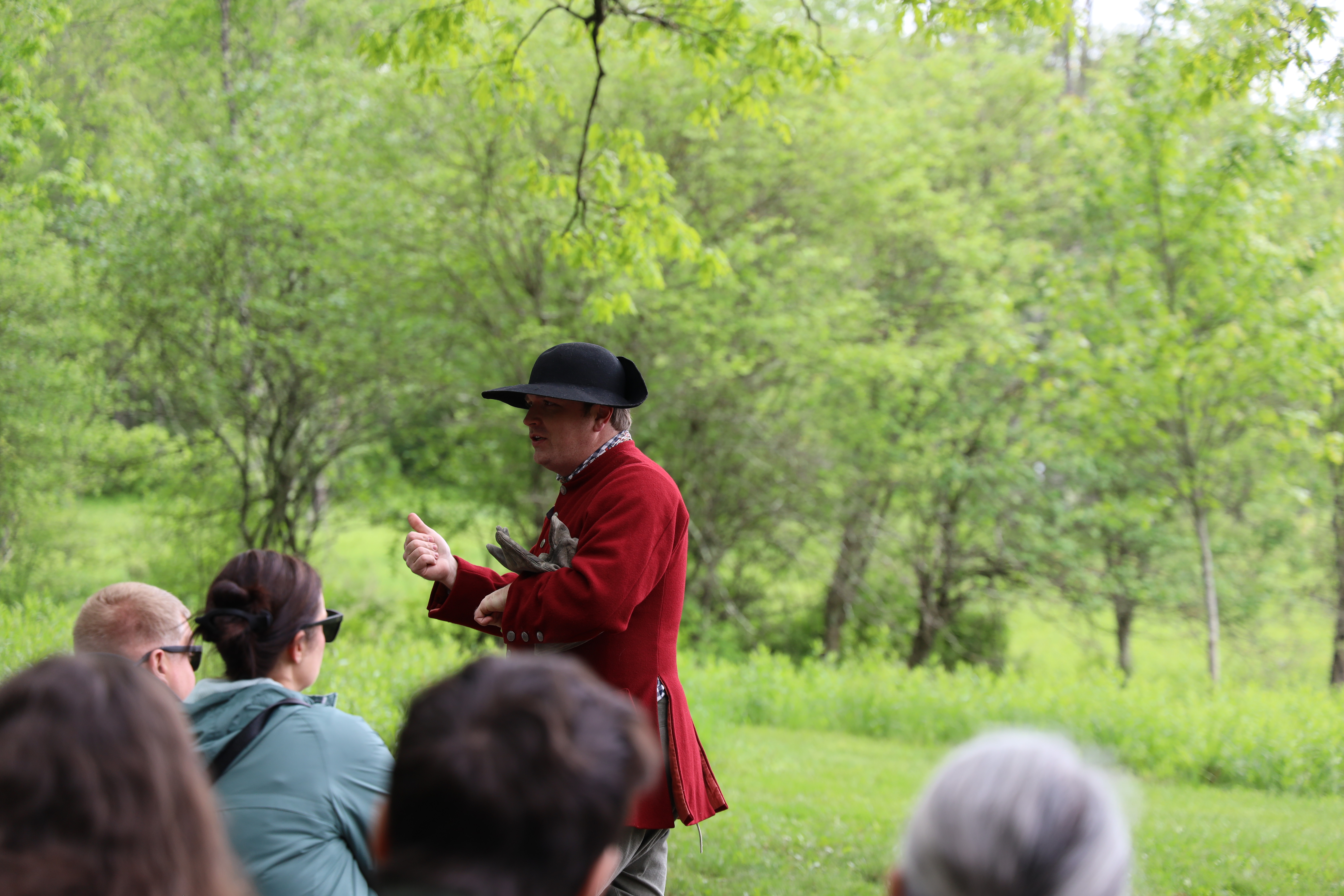 A park ranger in 18th century clothing gives a program in front of a group of visitors