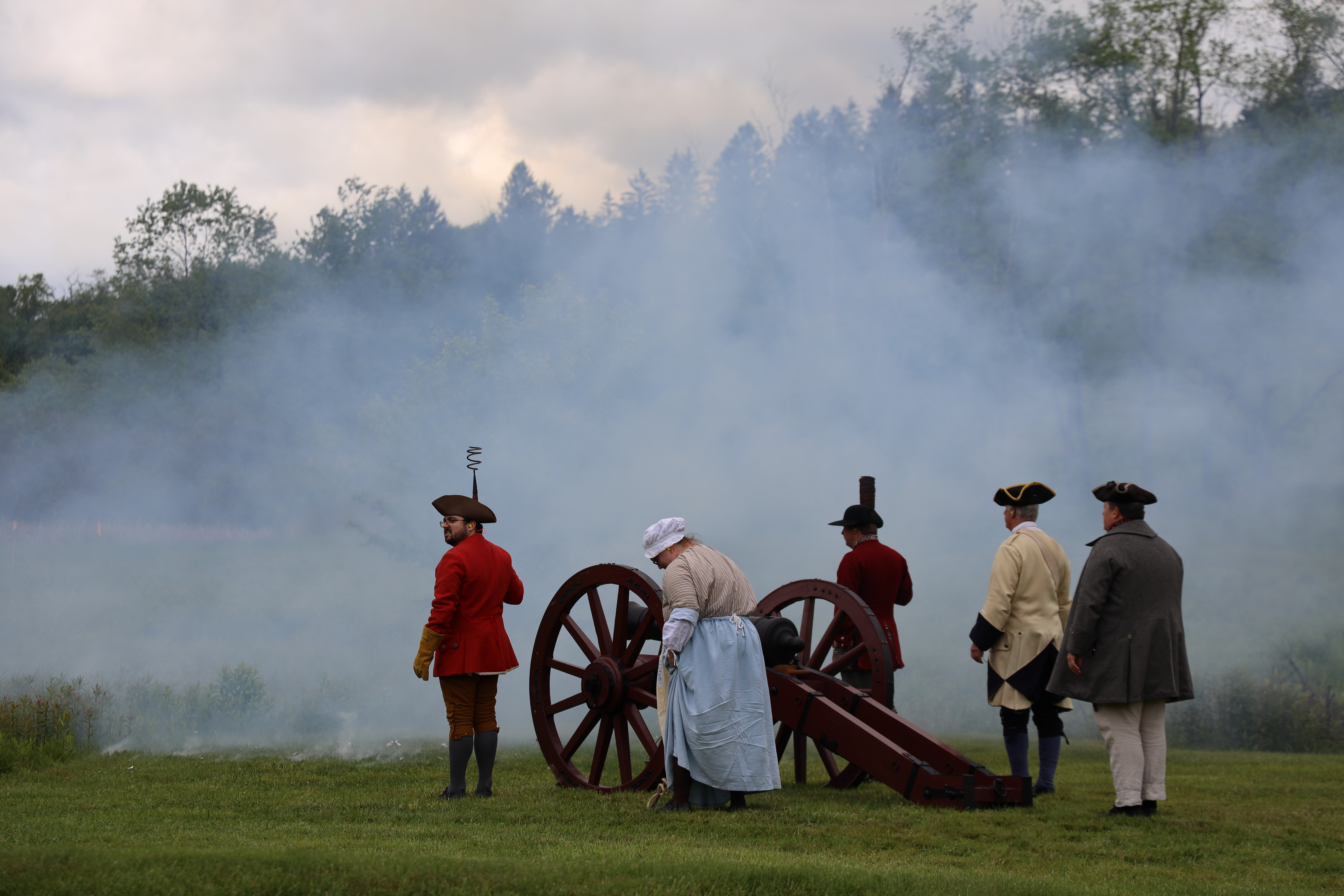 Rangers facing away standing around a recently fired cannon with smoke in front them