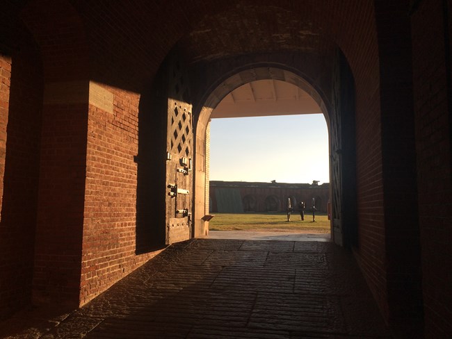 A brick doorway with a wooden door, lit by sunset colors.