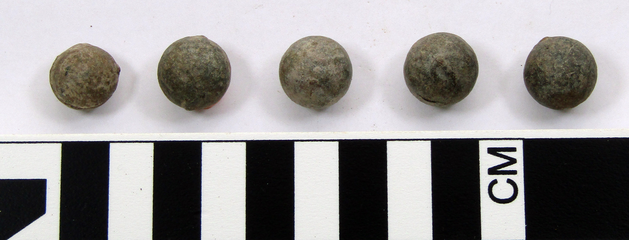 five gray musket balls, less than an inch in diameter.