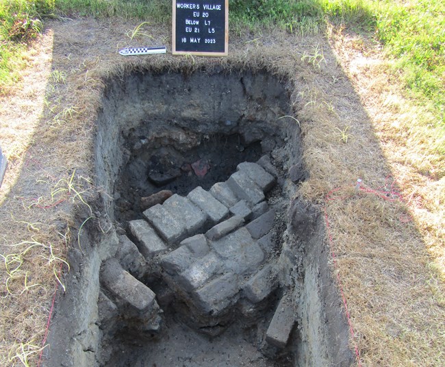 Hole in the ground with poorly aligned bricks.