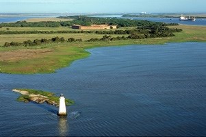 Aerial image of the Cockspur Island Lighthouse with the island in the background showing Fort Pulaski and the surround forest and salt marshes.