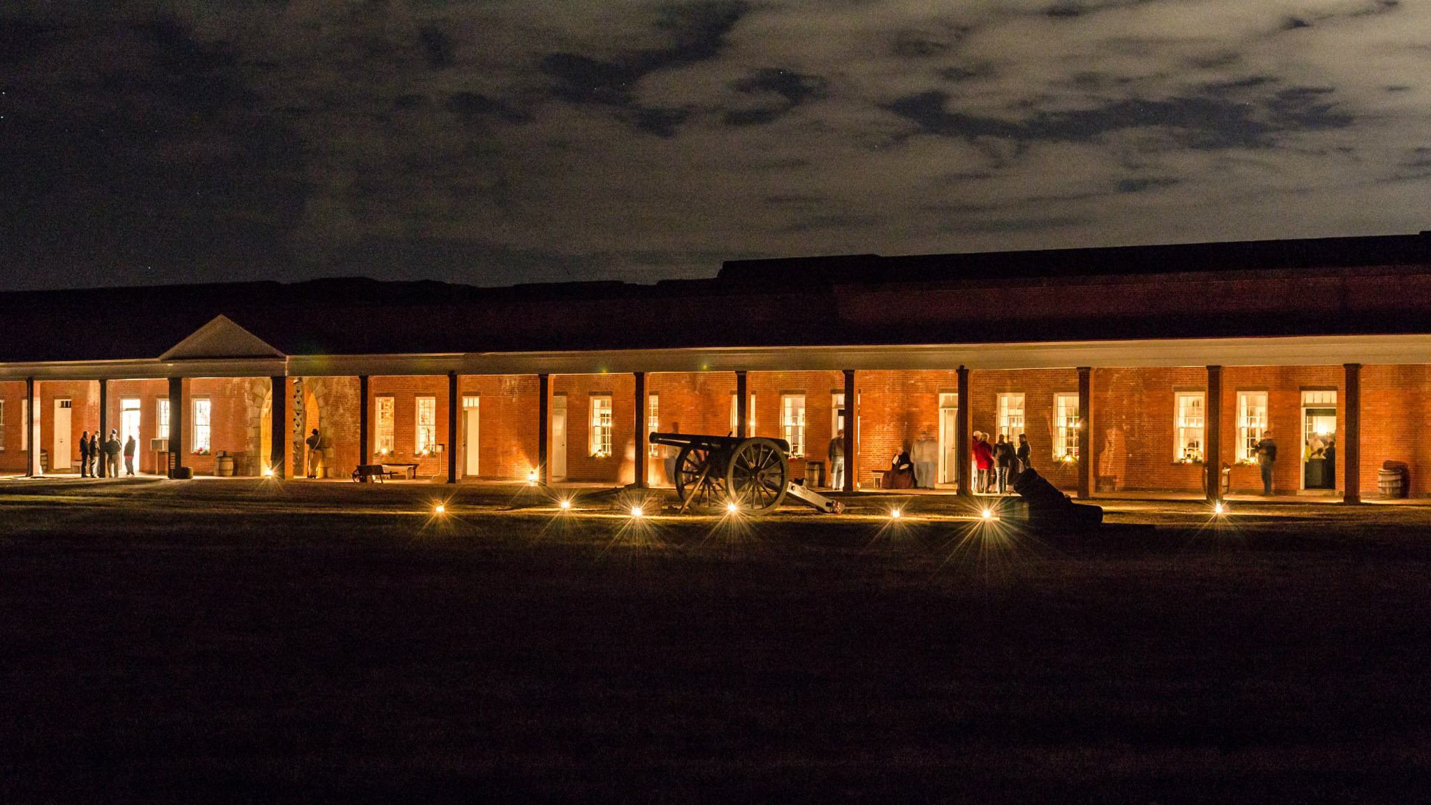 Candle Lantern The rooms of Fort Pulaski glow with candlelight as people enjoy a program at a nighttime Fort Pulaski. Cannon are silhouetted against the bright night backdrop.