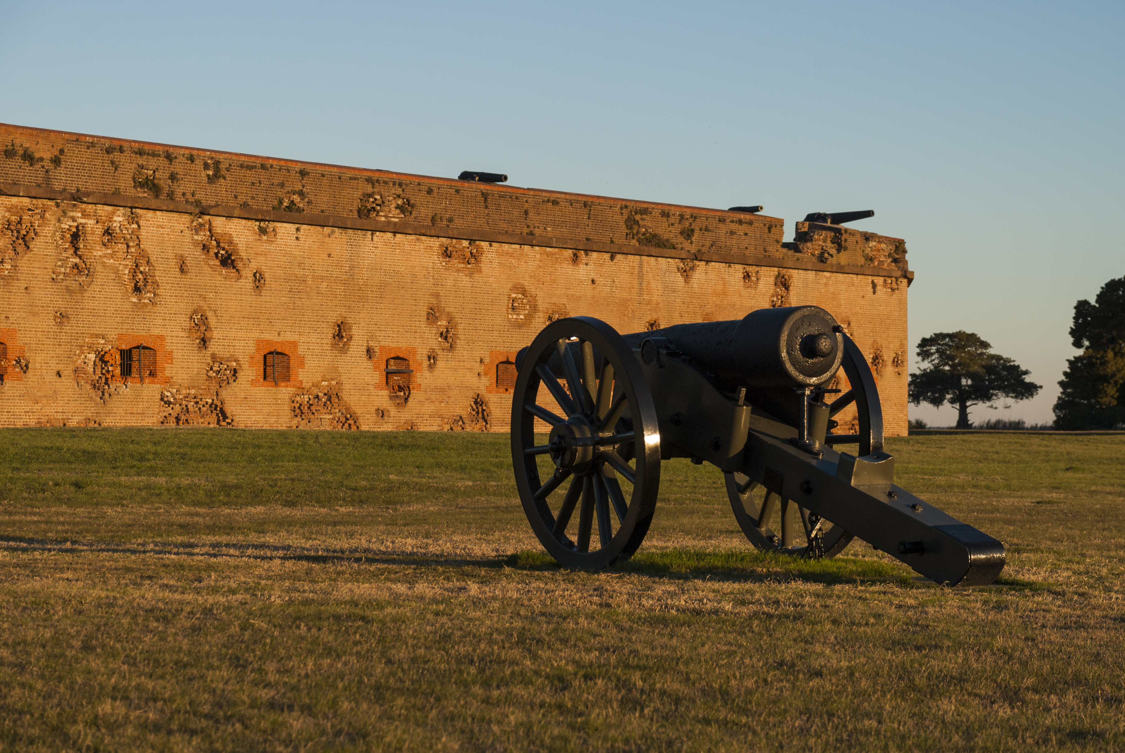 A cannon faces a brick fort's damaged outer walls.