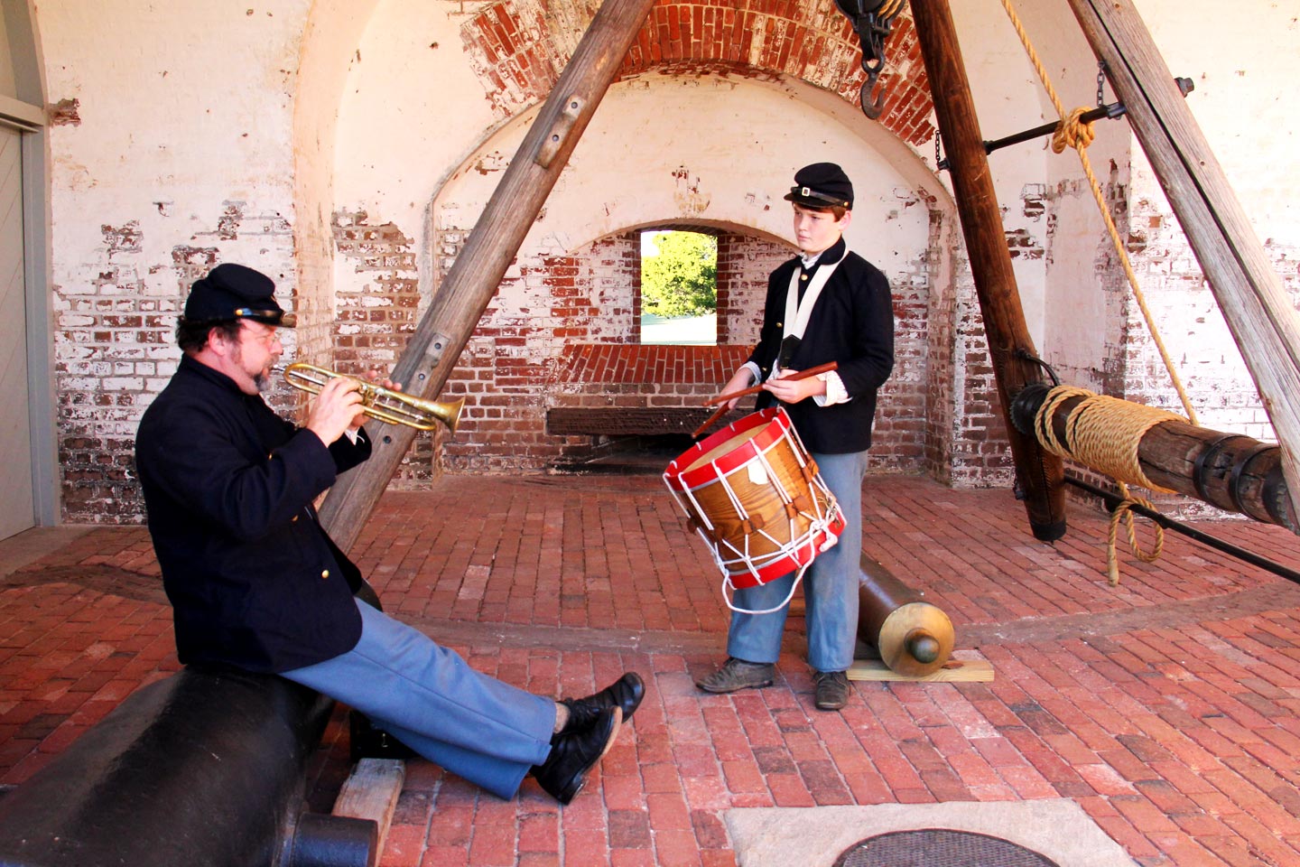 Music Practice With the 48th Two males dressed in Union Uniforms, the man on the left playing a bugle while the boy on the right plays a drum, inside a brick casemate of Fort Pulaski.