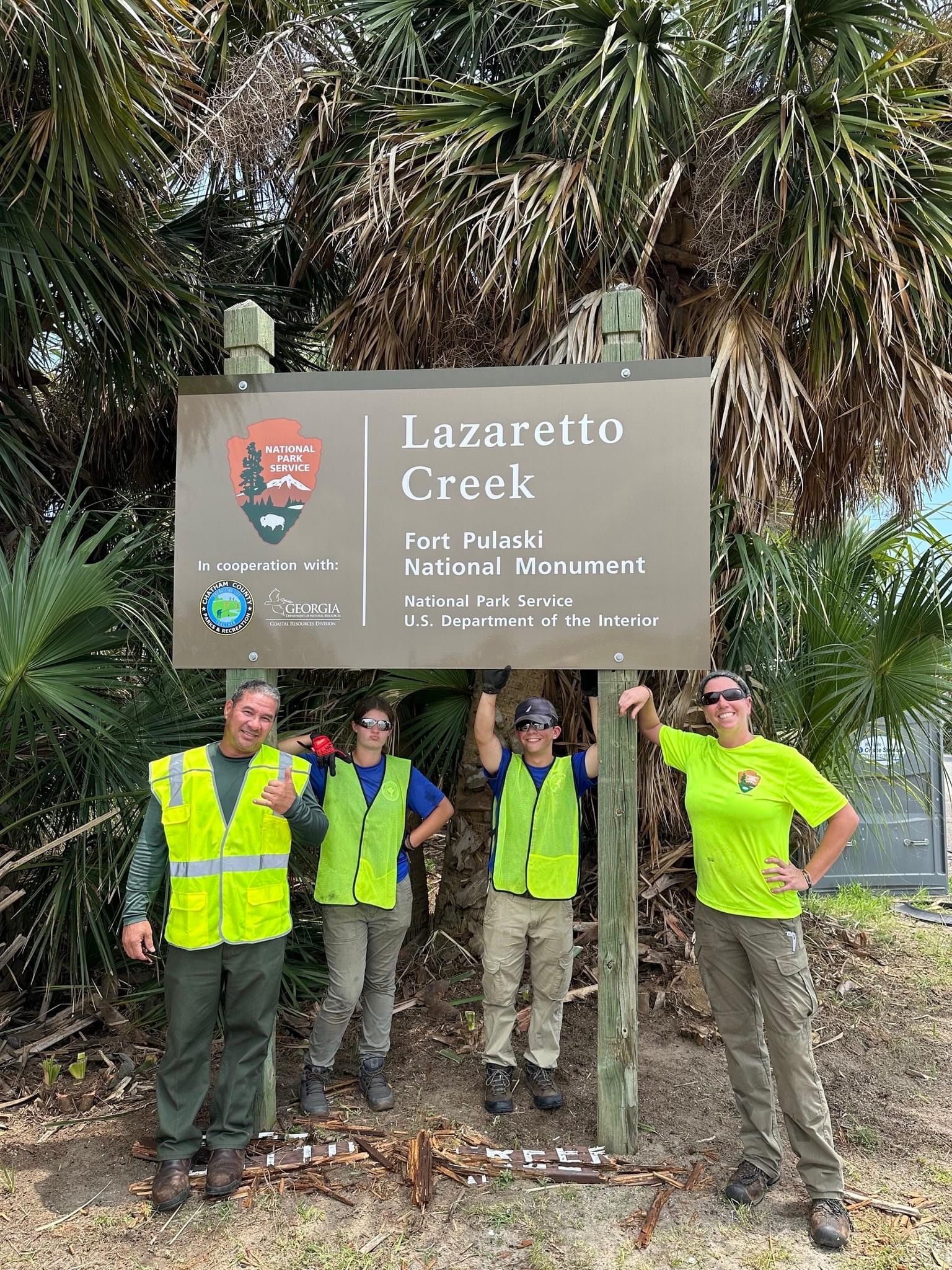 park staff and youth workers stand near a brown park sign.