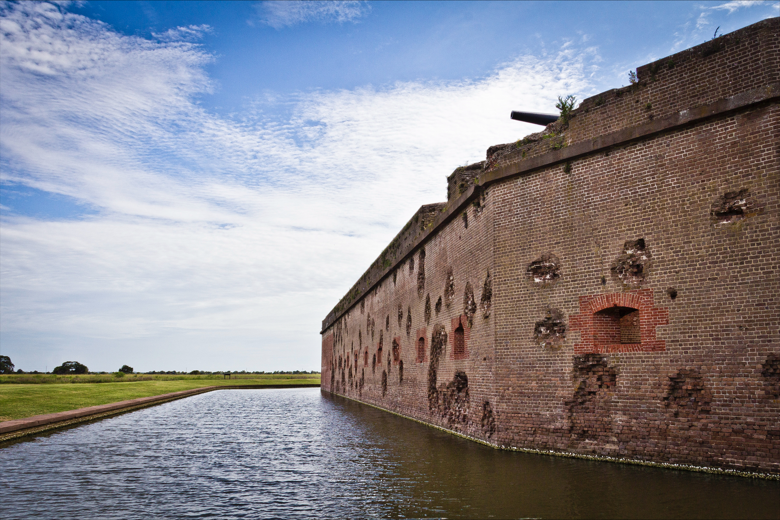 A brick and stone fort stands alongside a moat