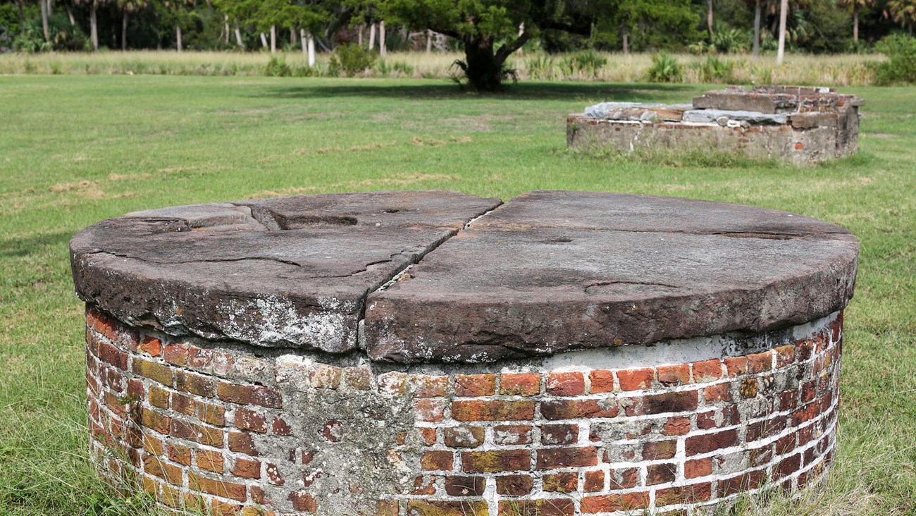 Two circular masonry cisterns rise  three feet in a grassy field