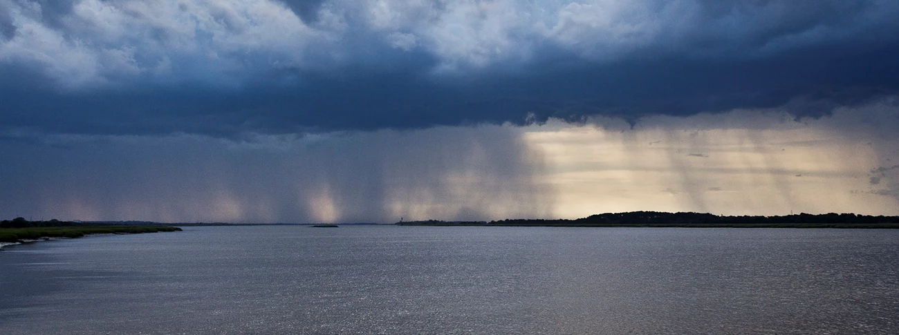 A photograph of storm clouds and rain approaching Cockspur Island from Savannah, Georgia. A photograph of storm clouds and rain approaching Cockspur Island from Savannah, Georgia.
