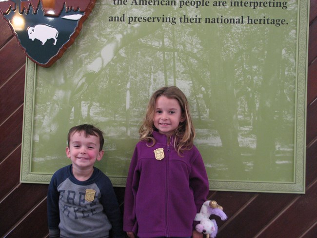 Two young children wearing junior ranger badges smiling
