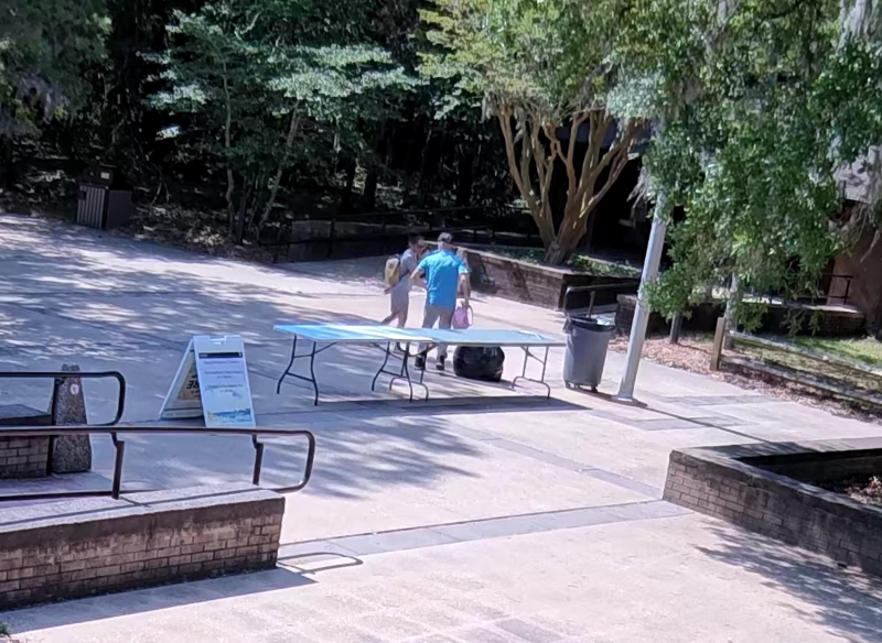 A white male walks away from a table carrying allegedly stolen personal items.