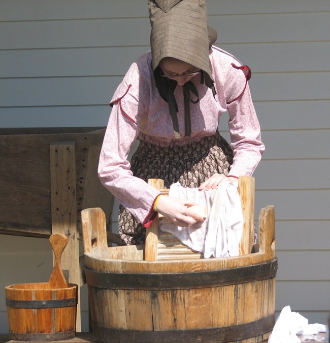 Laundress washes clothes on washboard with lye soap