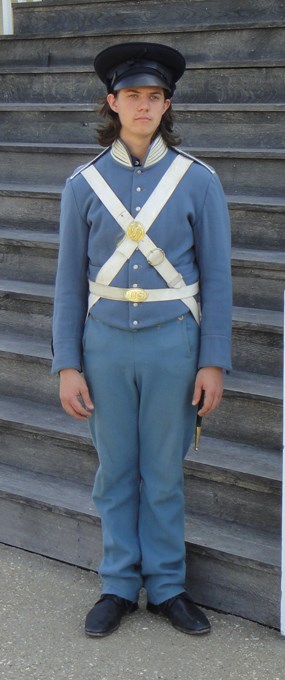 Man in infantry soldier's dress stands in front of a set of stairs.
