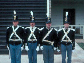 Soldiers stand at attention outside a building at Fort Scott