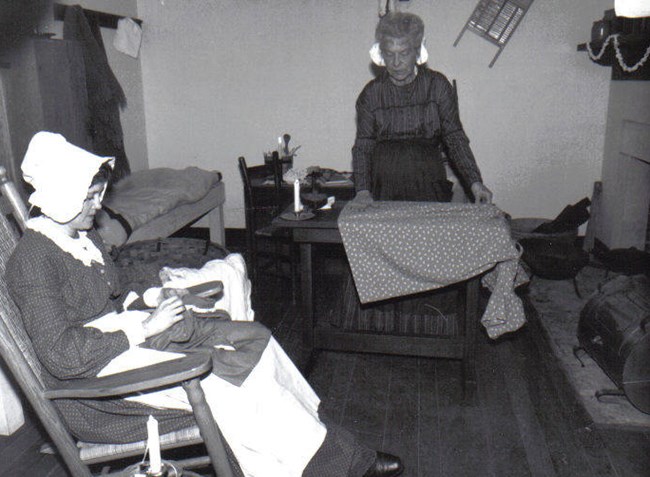 Two laundresses mend clothing in laundress quarters Two laundresses mend clothing in laundress quarters
