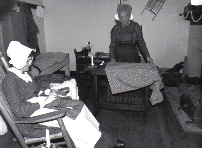 Two laundresses mend clothing in laundress quarters