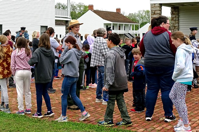 A park ranger stands at the entrance to Fort Scott as students and teachers arrive for educational programs
