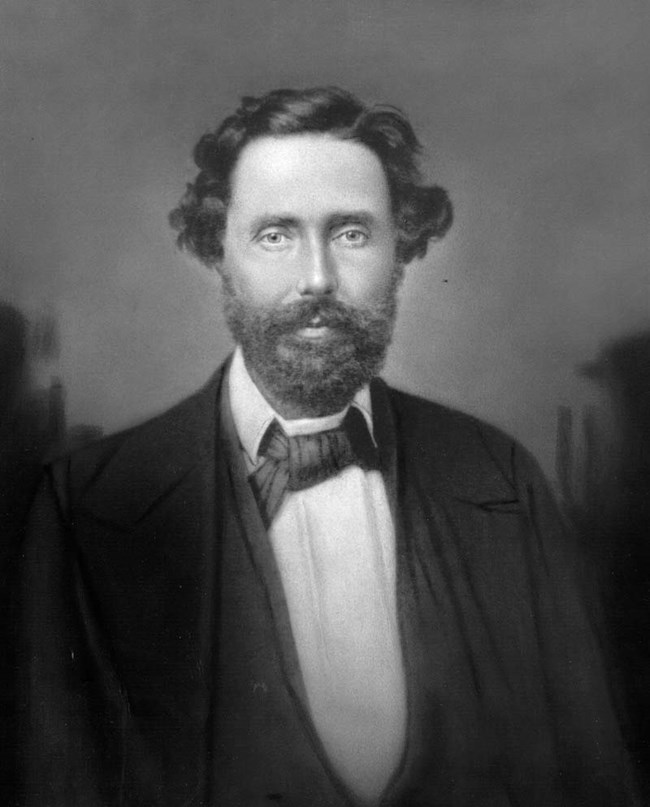 Man with dark hair and beard wearing suit