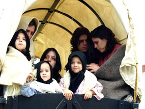 Color photo shows several people huddled in a wagon.