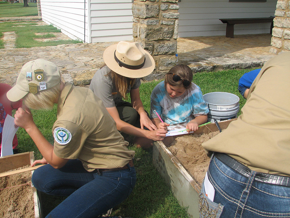 Youth archeological dig Youth and a Park Ranger are working on a mock archeological dig.