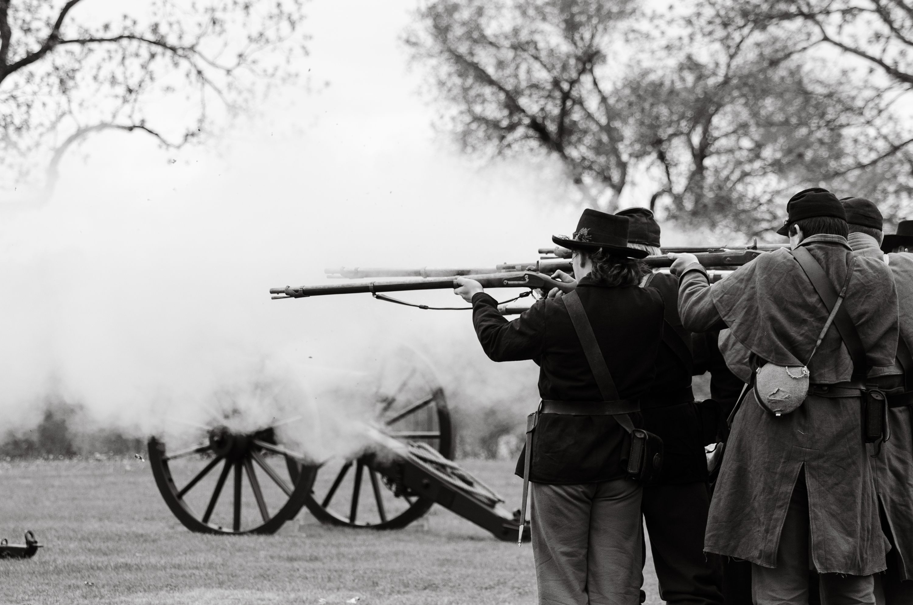 A group 0f volunteers in Civil War Infantry uniforms firing muskets.